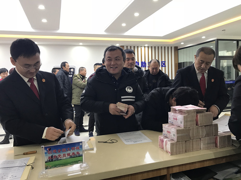 丁先生拿到被拖欠多年的工資款后露出久違的笑容