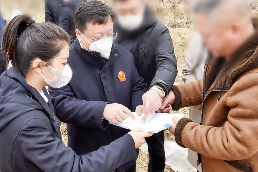 新民市法院大民屯法庭庭長王旌棘（左二）與委托代理人、村委會干部核對土地面積——馬震宇攝