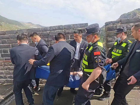 民警與景區(qū)工作人員將患病游客抬下長城。