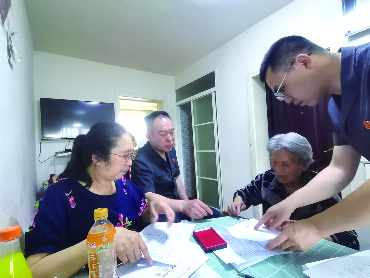 付承志（右一）胡善福（左二）指導(dǎo)潘某榮（右二）在調(diào)解書上簽字、按手印