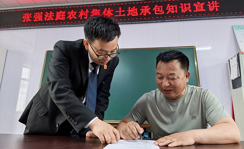 張強(qiáng)人民法庭庭長田芝濤（左）指導(dǎo)村民如何填寫“普法清單”